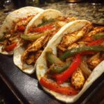 Close-up of three 20-Minute Sheet Pan Chicken Fajitas filled with chicken and vegetables.