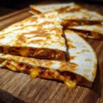 Close-up of golden, cheesy 3-Ingredient BBQ Chicken Quesadillas on a wooden board.