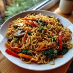 A plate of flavorful 3-ingredient ramen stir-fry with noodles, carrots, red peppers, and spinach.