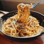 Close-up of 5-Minute Lazy Girl Pasta with Garlic Parmesan in a pan, with pasta being lifted by a fork.