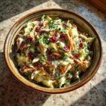 Overhead shot of a bowl of Apple Cranberry Coleslaw with cranberries, apples, and carrots.