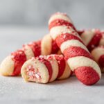 Close-up of festive Candy Cane Cookies, showing red and white stripes and crushed candy cane topping.