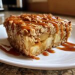 A slice of Caramel Apple Cinnamon Oatmeal Bake drizzled with caramel sauce on a white plate.