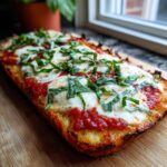 Close-up of a delicious Cauliflower Crust Margherita Flatbread topped with fresh basil.