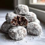 Pile of Chocolate Peppermint Snowball Cookies dusted with powdered sugar, one cut open.