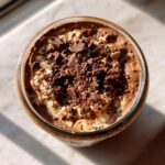 Overhead shot of a jar filled with Chocolate Protein Overnight Oats, topped with chocolate chunks.