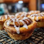 Close-up of freshly baked Cinnamon Roll Sugar Cookie Cups with icing on a cooling rack.
