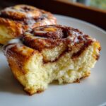 Close-up of a Cloud Bread Cinnamon Roll with a bite taken, showing the soft interior and icing. The primary keyword is Cloud Bread Cinnamon Rolls.