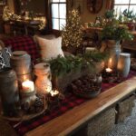 A cozy farmhouse Christmas living room decorated with trees, lights, plaid, and natural elements.