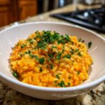 Close-up of a bowl of creamy pumpkin risotto, garnished with fresh parsley.