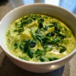 A bowl of creamy spinach artichoke soup, a delicious and comforting dish.