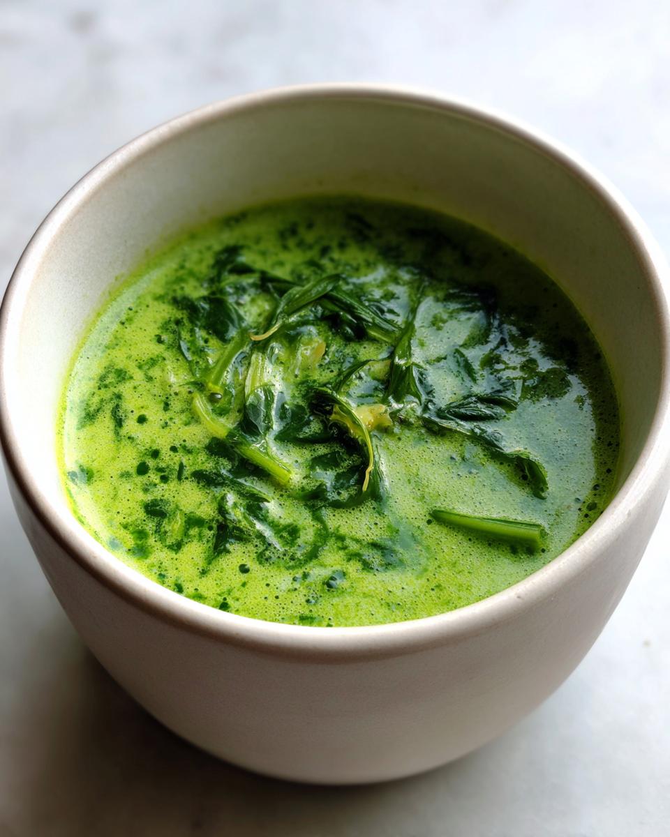 Close-up of a bowl of Creamy Spinach Artichoke Soup, a vibrant green soup.
