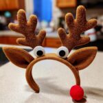 A cute DIY reindeer headband for kids, featuring fuzzy antlers, googly eyes, and a red nose.