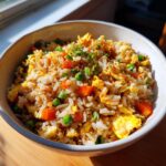 A bowl of Easy Veggie Fried Rice with Egg, featuring rice, vegetables, and egg.