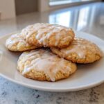 Pile of delicious Frosted Eggnog Sugar Cookies on a white plate, drizzled with sweet glaze.