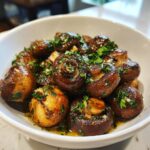 Close-up of Garlic Butter Mushrooms in a white bowl, garnished with fresh herbs.