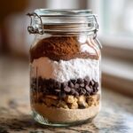 Close-up of a glass jar filled with layered ingredients for a giftable cookie mix.