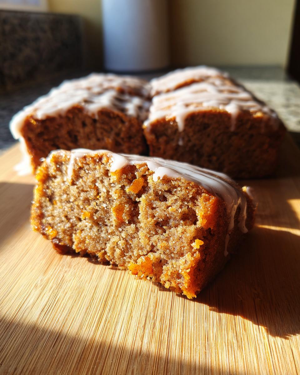 Close-up of a slice of Gingerbread Cookie Bars, drizzled with white glaze, on a wooden cutting board.