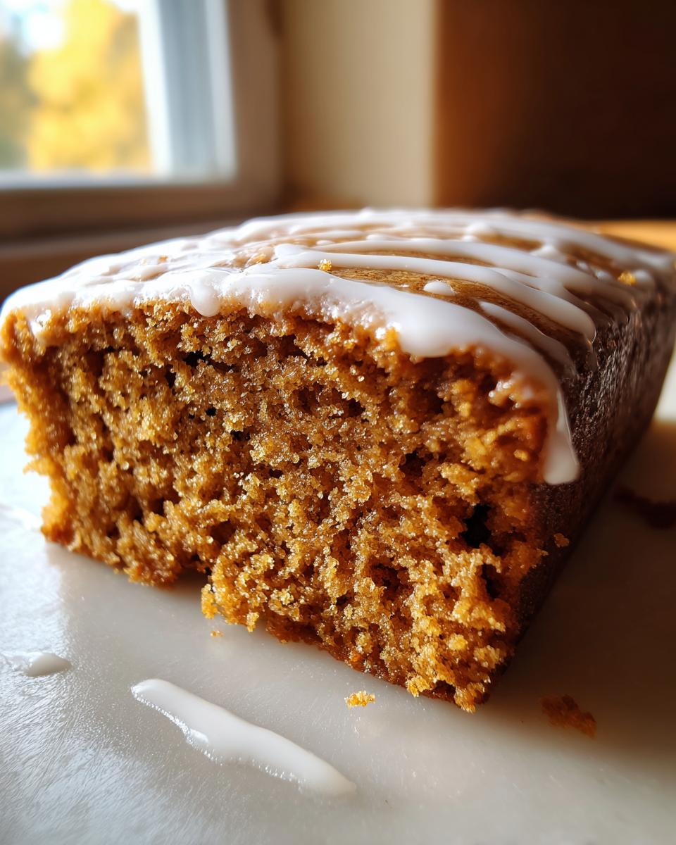 A close-up of a slice of moist Gingerbread Cookie Bars topped with a white glaze drizzle.