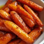 Close-up of a bowl of glistening Glazed Carrots, showing the sweet glaze and seasoning.