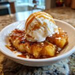 A Grilled Pineapple Caramel Sundae in a white bowl, topped with ice cream and caramel sauce.