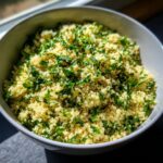 Close-up of a bowl of delicious Herbed Couscous, garnished with fresh herbs.