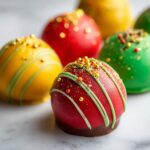 Close-up of colorful Holiday Ornament Oreo Truffles decorated with green icing and gold sprinkles.