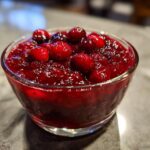Close-up of a glass bowl filled with vibrant Homemade Cranberry Sauce.