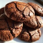 A close-up, mouth-watering shot of several rich, dark chocolate Hot Cocoa Cookies with a cracked surface.