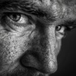 Close-up black and white portrait of a man's face, focusing on his eye and nose.