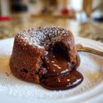 Close-up of a 4-Ingredient Nutella Lava Cake with molten chocolate center, dusted with powdered sugar.