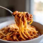 Close-up of One-Pot Pasta e Fagioli Soup on a fork, showing pasta, beans, and sauce.