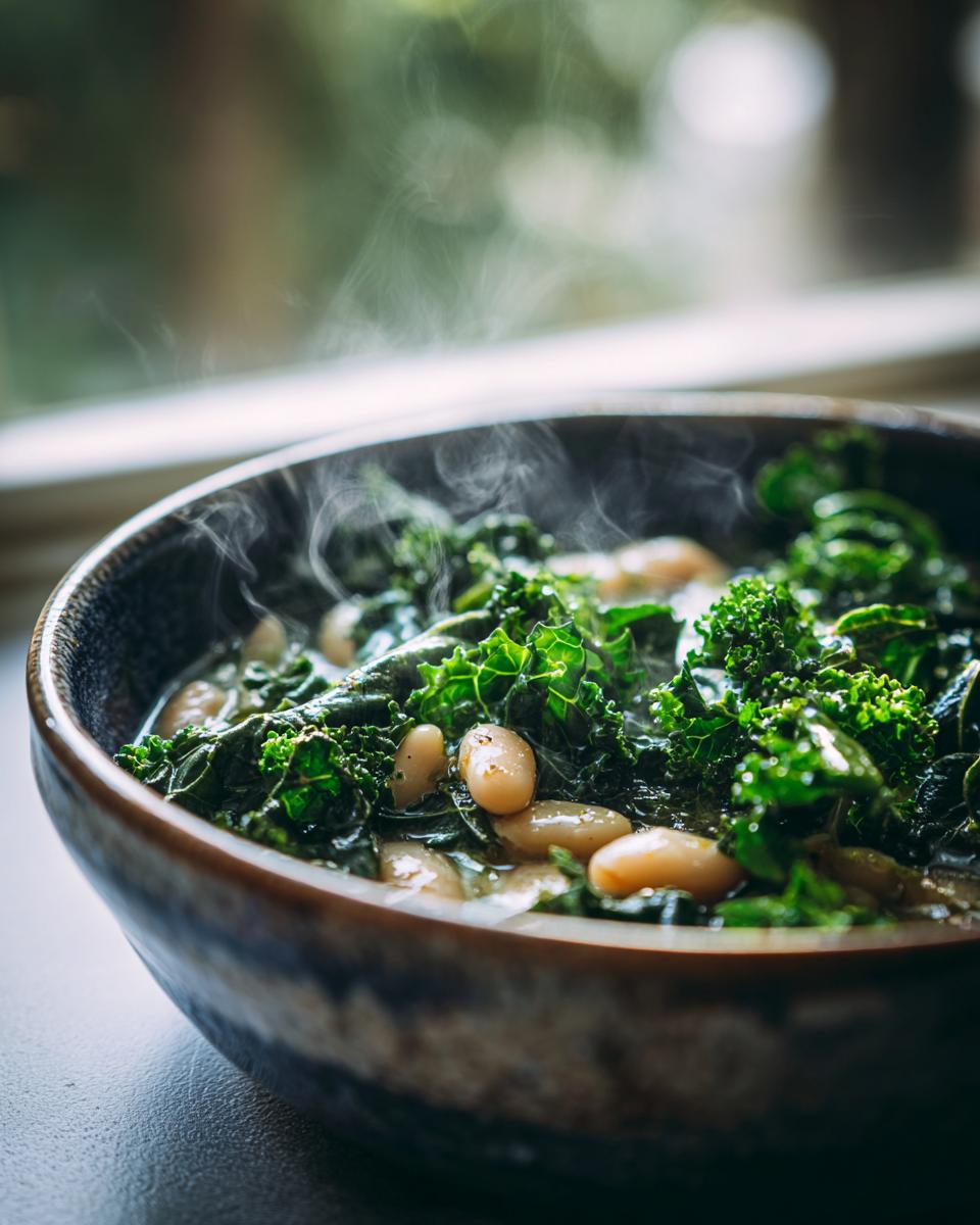 Close-up of a bowl of One-Pot White Bean & Kale Soup, with steam rising from the hot soup.