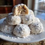 Close-up of a stack of Pecan Snowball Meltaway Cookies dusted with powdered sugar.
