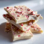 A stack of white chocolate peppermint bark pieces, topped with crushed candy canes. Perfect for a quick Peppermint Bark Recipe in 5 Minutes.
