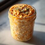 Close-up of a jar of Pumpkin Spice Latte Overnight Oats, topped with seeds.