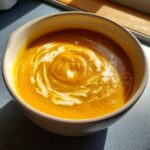 A bowl of creamy Roasted Butternut Squash Soup swirled with cream.