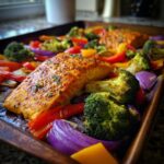 Close-up of sheet pan turmeric salmon with roasted broccoli, peppers, and onions.