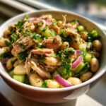 Close-up of a bowl of Simple Tuna and White Bean Salad with tuna, white beans, red onion, and parsley.