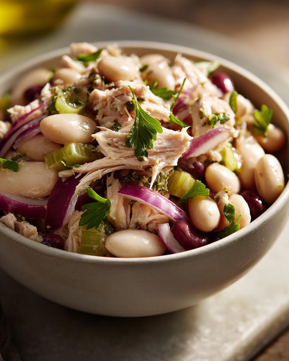 Close-up of a Simple Tuna and White Bean Salad in a bowl, with tuna, beans, and red onion.