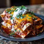 Close-up of Slow Cooker Bean and Cheese Enchiladas topped with sour cream and cilantro.