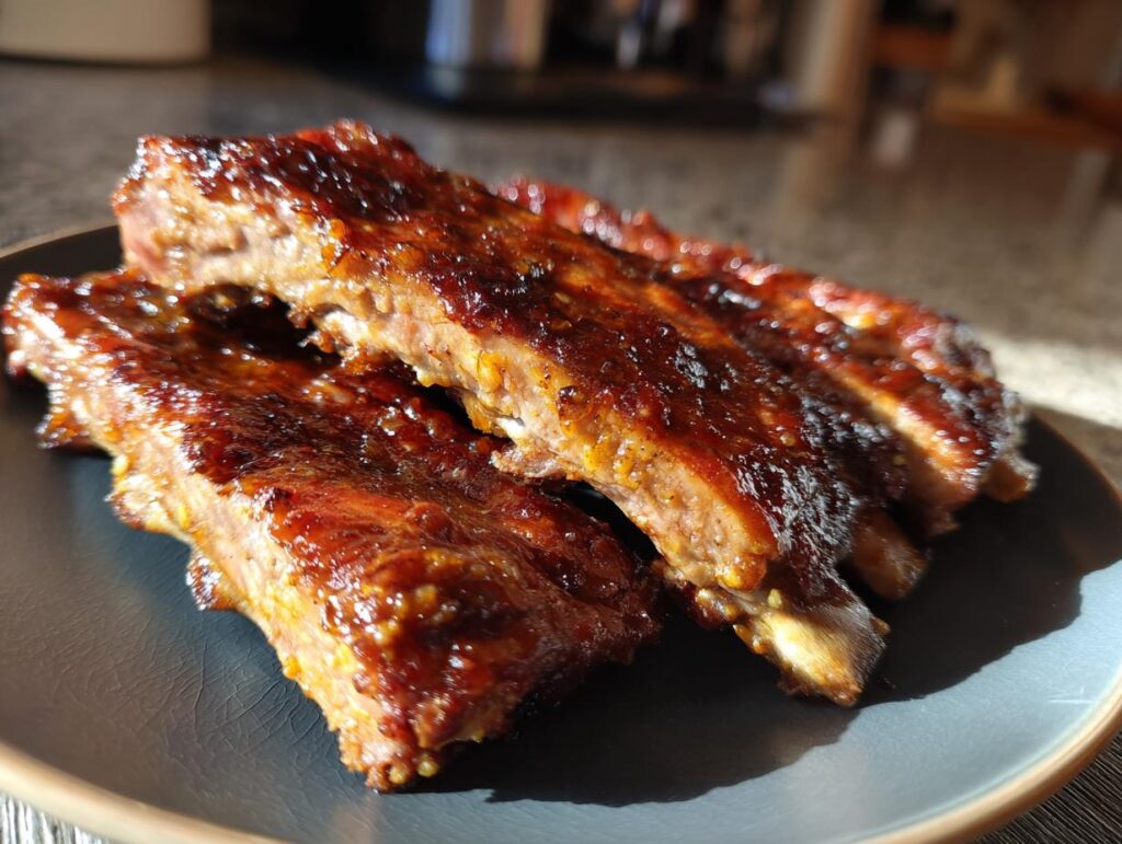 Close-up of tender Slow Cooker Honey Garlic Pork Ribs on a plate, glazed with a sweet and savory sauce.