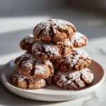 A stack of Soft and Spiced Gingerbread Crinkle Cookies dusted with powdered sugar.