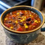 Close-up of a bowl of Spicy Black Bean & Corn Soup with corn, tomatoes, and beans.