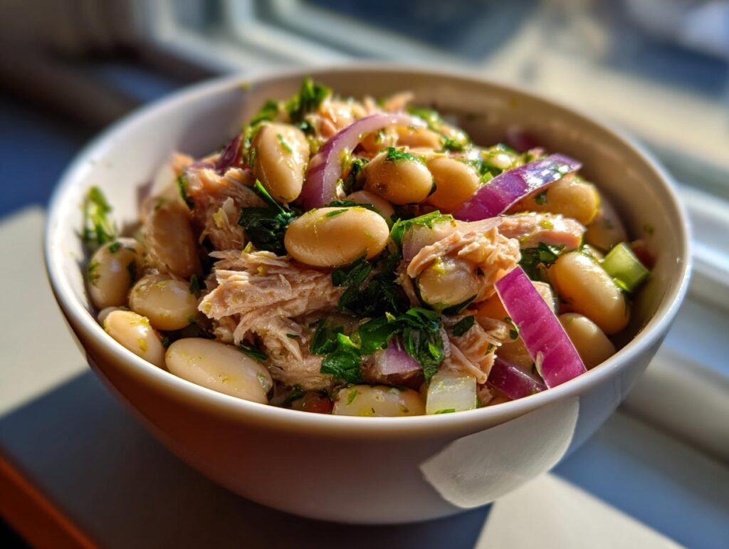 Close-up of a bowl filled with Simple Tuna and White Bean Salad, featuring tuna, white beans, red onion, and herbs.