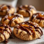 Close-up of several Turtle Thumbprint Cookies topped with gooey caramel and drizzled with chocolate.