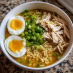 Overhead shot of an Upgraded Ramen Bowl with Garlic Butter, featuring noodles, egg, chicken, and green onions.