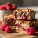 Close-up of stacked Vegan Raspberry Chia Breakfast Bars with fresh raspberries.