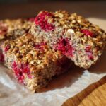 Close-up of a Vegan Raspberry Chia Breakfast Bar showing the raspberry filling and oat topping.
