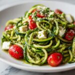 Close-up of a Zucchini Noodle Pesto Caprese with tomatoes, mozzarella, and pesto.
